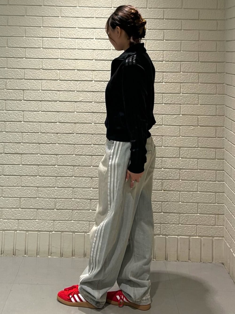 レッド系のスニーカー、ブラック系のジャージ、ブルー系のデニムパンツを着用したレディースの冬コーディネートの2枚目の写真