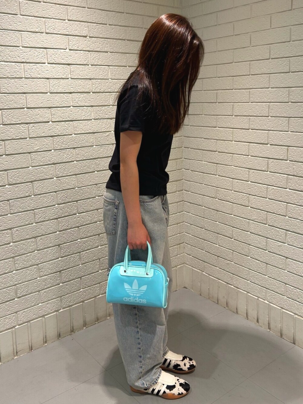 ホワイト系のシューズ、ブラック系のトップス、グリーン系のショルダーバッグを着用したレディースの春コーディネートの2枚目の写真