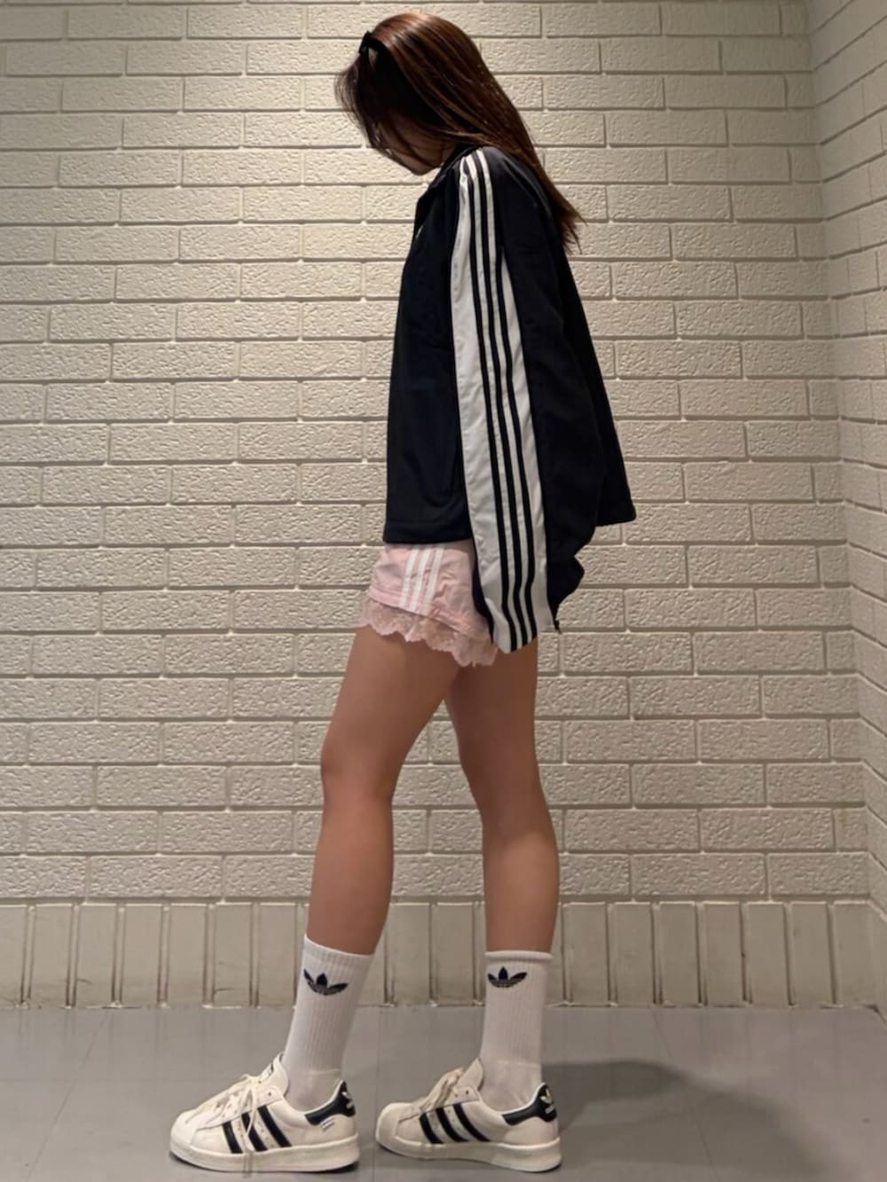 ブラック系のジャージ、ピンク系のその他パンツ、ホワイト系のシューズを着用したレディースの春コーディネートの2枚目の写真