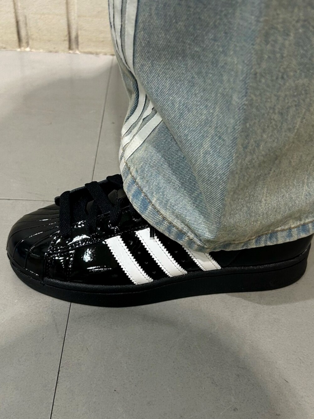 ブラック系のジャージ、ブルー系のデニムパンツ、ブラック系のスニーカーを着用したレディースの冬コーディネートの4枚目の写真