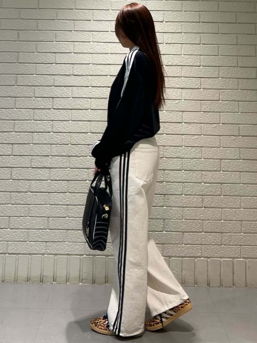 ベージュ系のスニーカー、ブラック系のトップス、ブラック系のショルダーバッグを着用したレディースの冬コーディネートの2枚目の写真