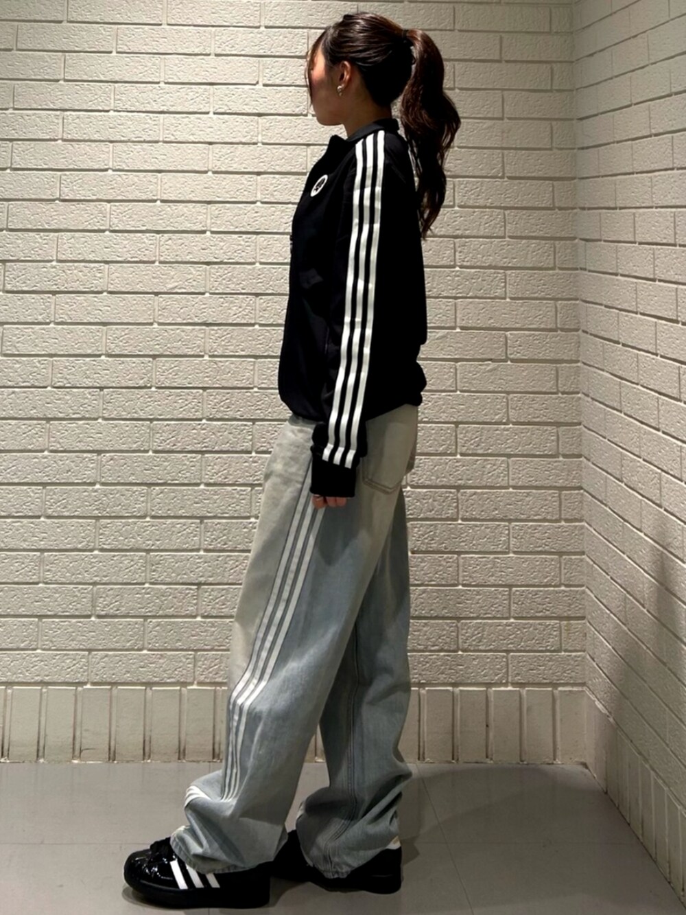 ブラック系のジャージ、ブルー系のデニムパンツ、ブラック系のスニーカーを着用したレディースの冬コーディネートの2枚目の写真