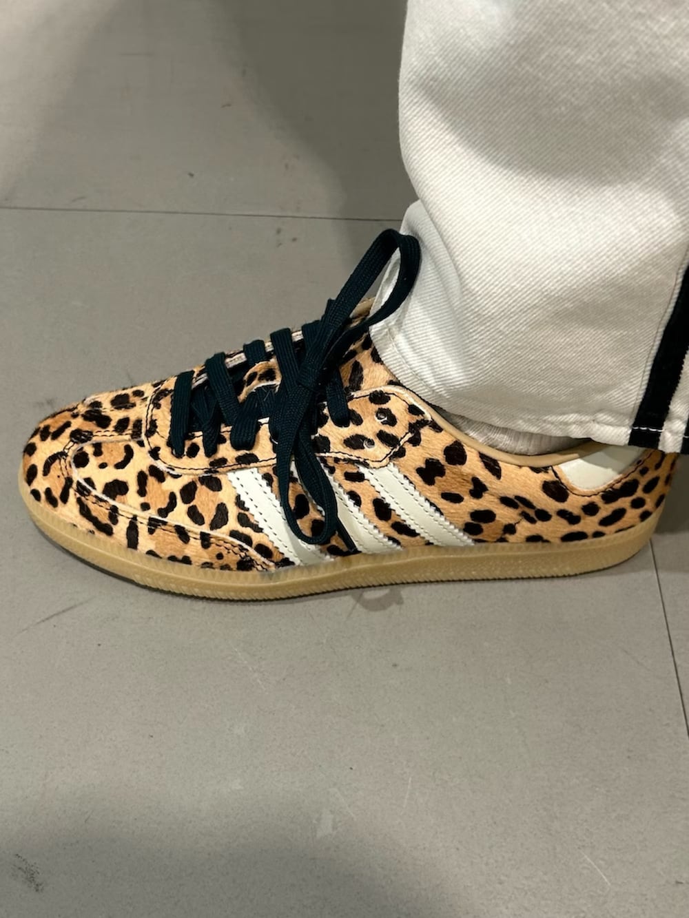 ベージュ系のスニーカー、ブラック系のトップス、ブラック系のショルダーバッグを着用したレディースの冬コーディネートの4枚目の写真