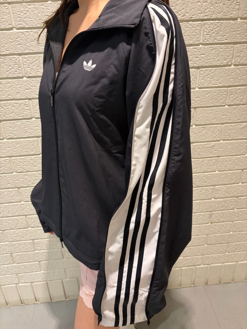 ブラック系のジャージ、ピンク系のその他パンツ、ホワイト系のシューズを着用したレディースの春コーディネートの3枚目の写真