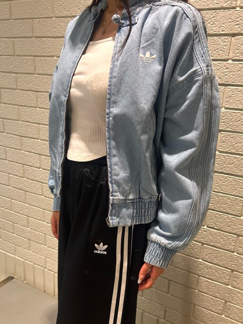 ブルー系のデニムジャケット、ブラック系のスウェットパンツ、ブラウン系のスニーカーを着用したレディースの秋コーディネートの3枚目の写真