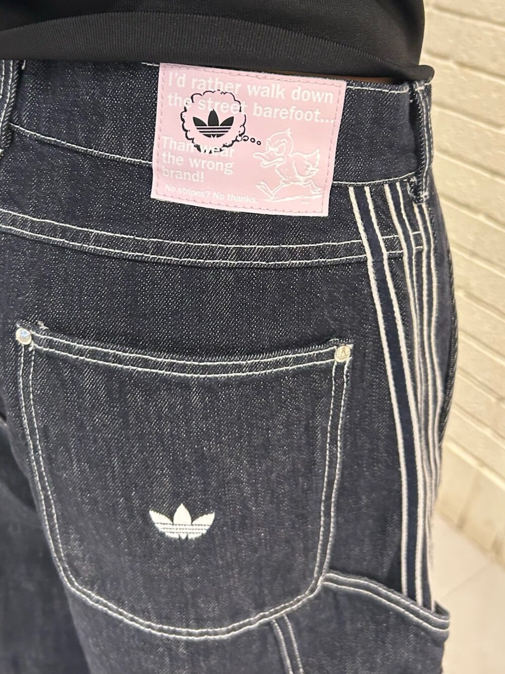 ベージュ系のスニーカー、ブラック系のジャージ、ブルー系のデニムパンツを着用したレディースの冬コーディネートの3枚目の写真