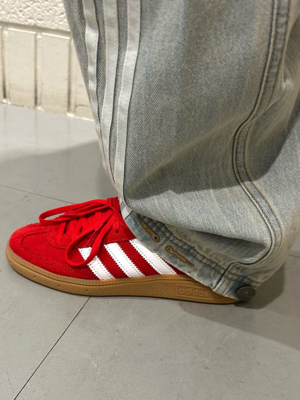 レッド系のスニーカー、ブラック系のジャージ、ブルー系のデニムパンツを着用したレディースの冬コーディネートの4枚目の写真