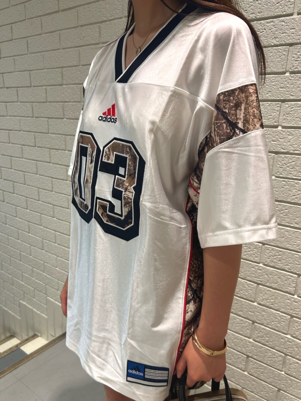 ホワイト系のトップス、ベージュ系のショルダーバッグ、ブラウン系のスニーカーを着用したレディースの夏コーディネートの3枚目の写真