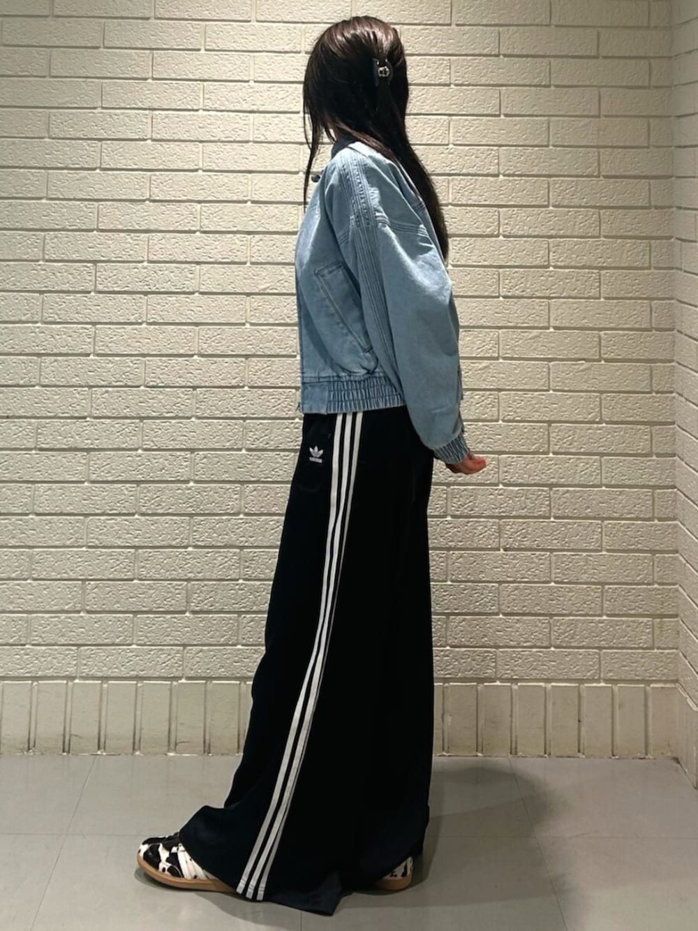 ブルー系のデニムジャケット、ブラック系のスウェットパンツ、ブラウン系のスニーカーを着用したレディースの秋コーディネートの2枚目の写真