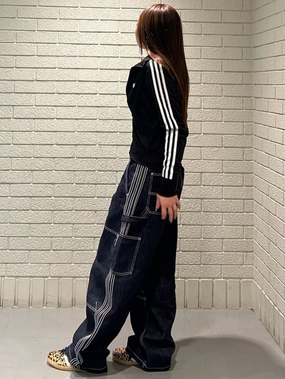 ベージュ系のスニーカー、ブラック系のジャージ、ブルー系のデニムパンツを着用したレディースの冬コーディネートの2枚目の写真