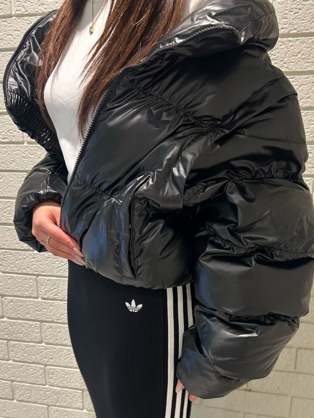 シルバー系のショルダーバッグ、ホワイト系のシューズ、ブラック系のダウンジャケット/コートを着用したレディースの秋コーディネートの2枚目の写真