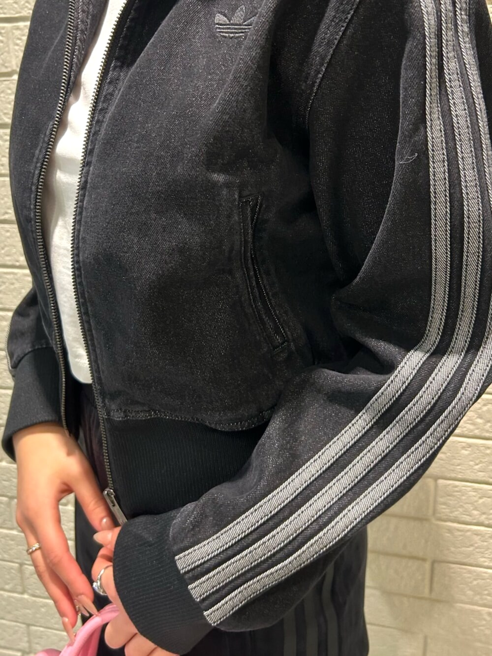 ブラック系のデニムジャケット、ホワイト系のTシャツ/カットソー、ブラック系のスウェットパンツを着用したレディースの冬コーディネートの3枚目の写真