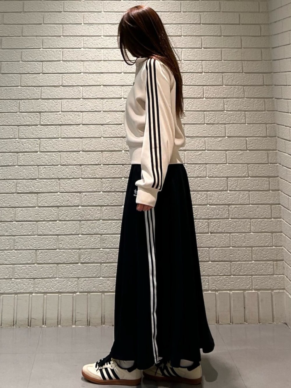 ホワイト系のスニーカー、ホワイト系のジャージ、ブラック系のスカートを着用したレディースの冬コーディネートの2枚目の写真