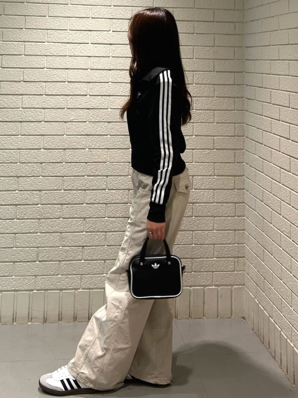 ブラック系のショルダーバッグ、ブラック系のジャージ、ホワイト系のシューズを着用したレディースの秋コーディネートの2枚目の写真