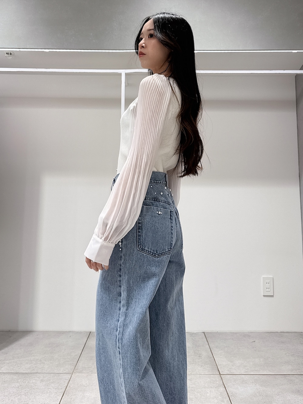 グリーン系のテーラードジャケット、ホワイト系のニット/セーター、ブルー系のデニムパンツを着用したレディースの春コーディネートの9枚目の写真