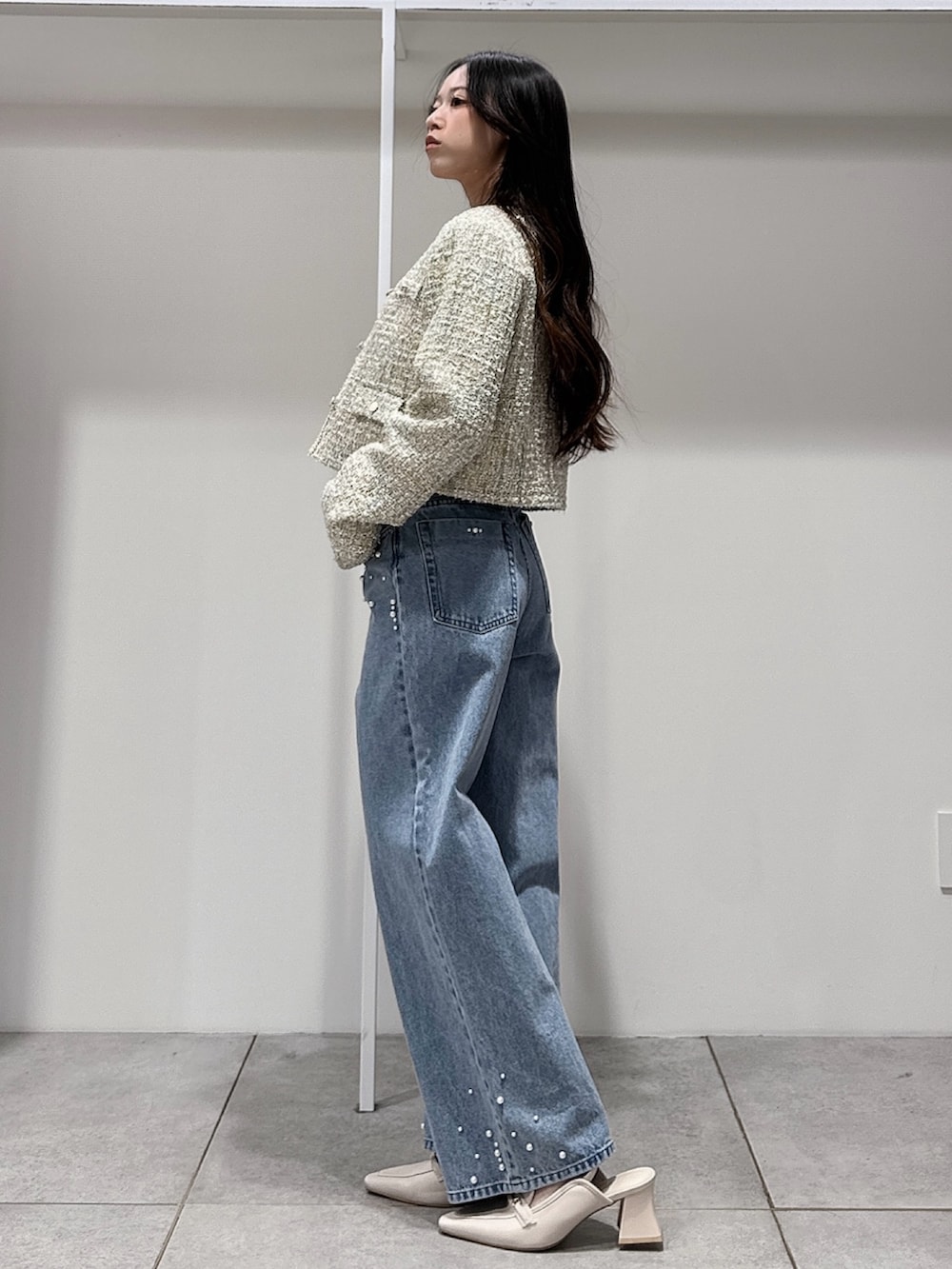 グリーン系のテーラードジャケット、ホワイト系のニット/セーター、ブルー系のデニムパンツを着用したレディースの春コーディネートの2枚目の写真