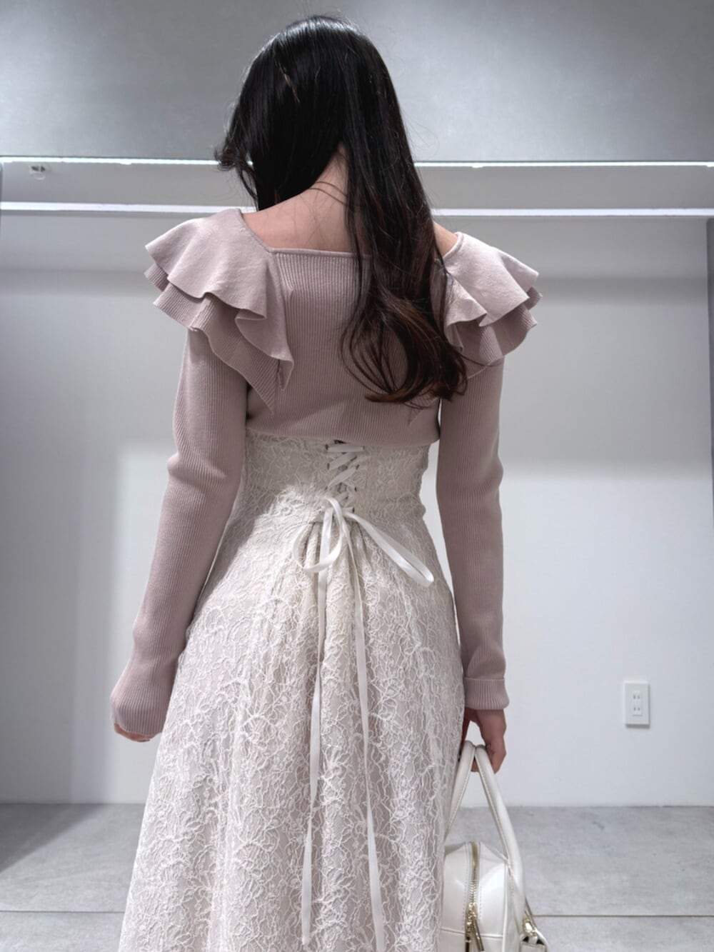 ホワイト系のハンドバッグ、ホワイト系のブーツ、ベージュ系のニット/セーターを着用したレディースの冬コーディネートの6枚目の写真