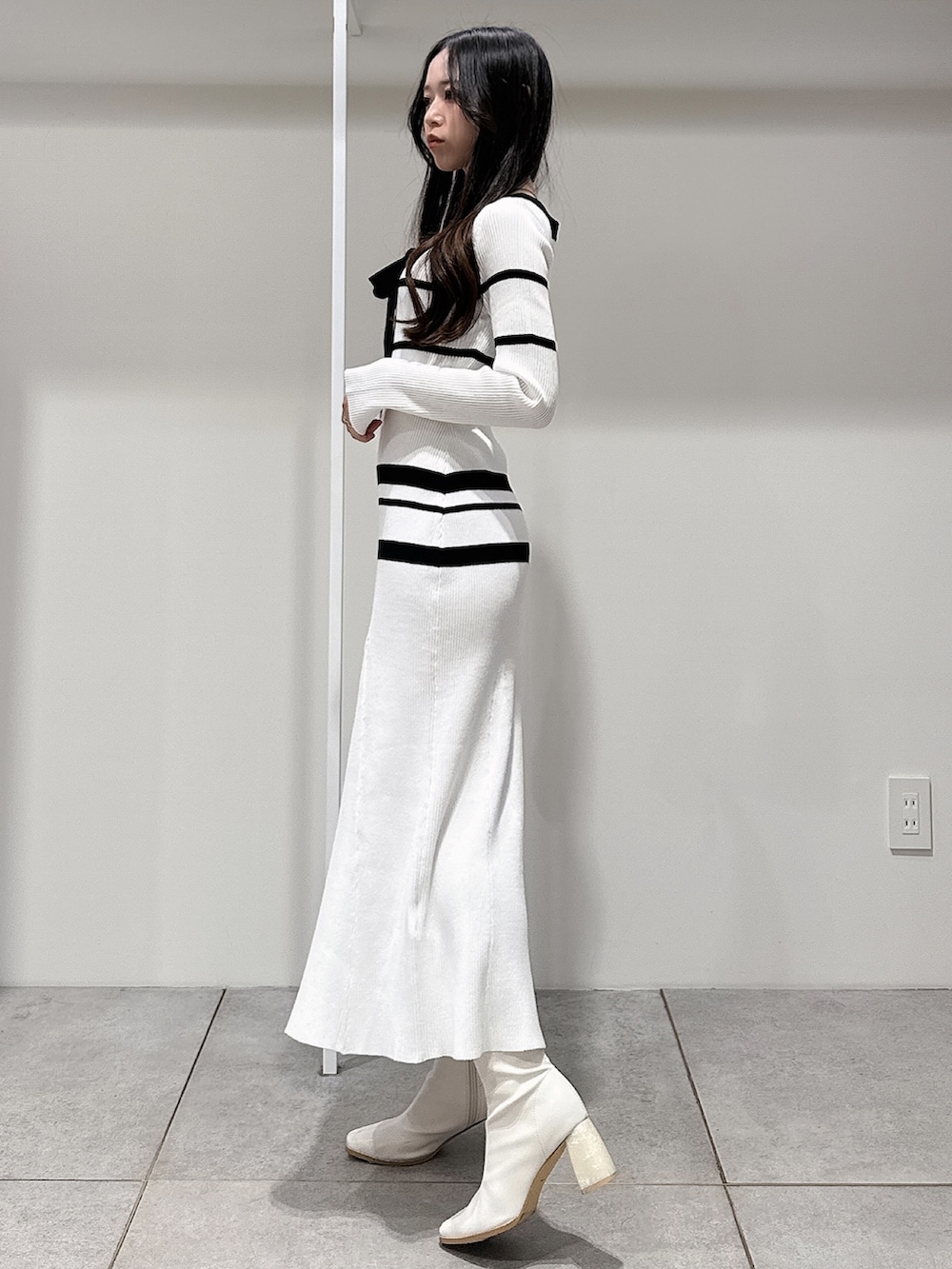 ブルー系のトレンチコート、ホワイト系のブーツ、ホワイト系のワンピースを着用したレディースの冬コーディネートの9枚目の写真