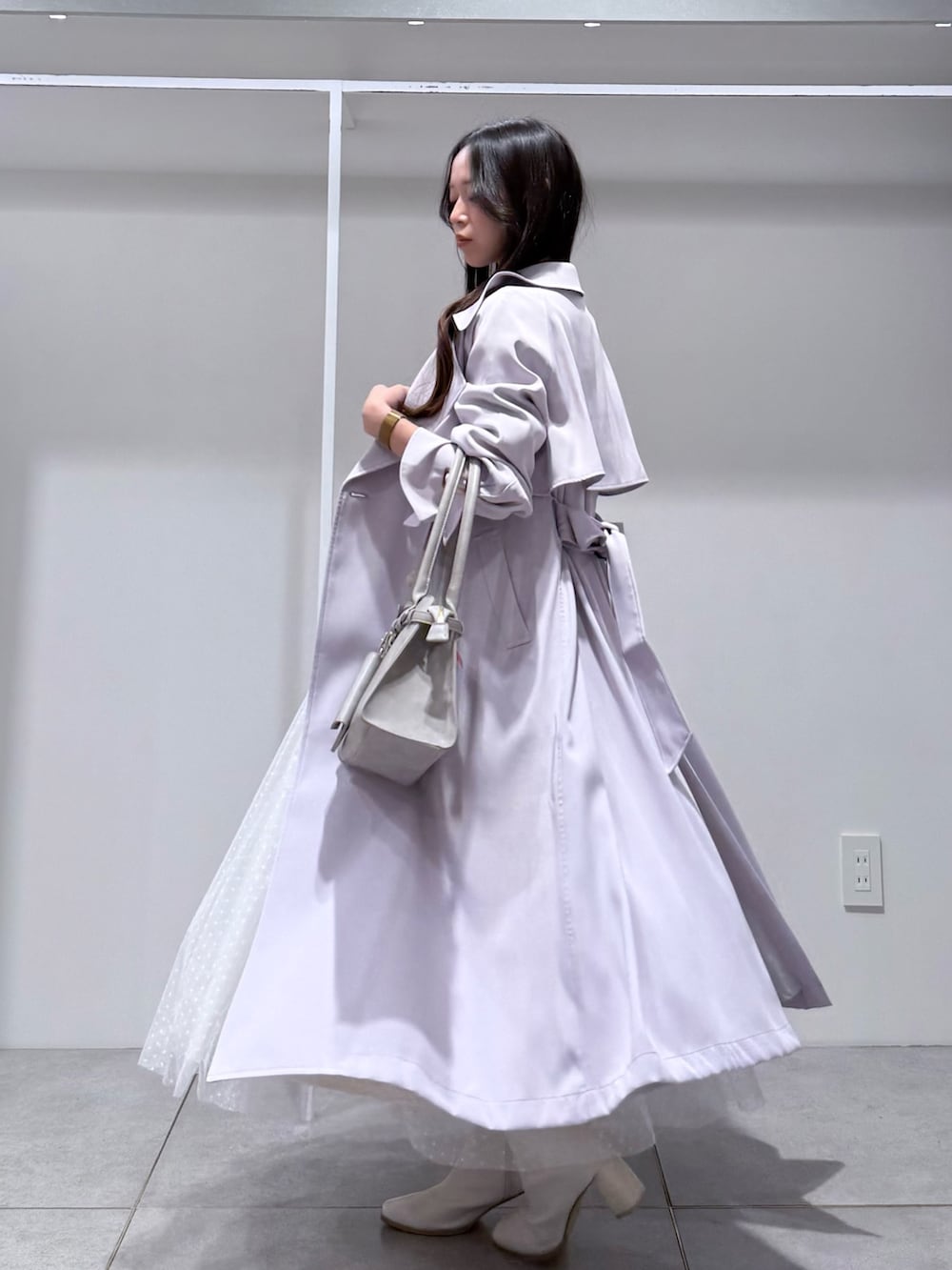 パープル系のトレンチコート、ホワイト系のワンピース、グレー系のハンドバッグを着用したレディースの冬コーディネートの4枚目の写真
