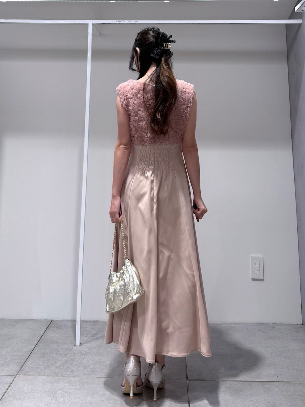 ホワイト系のトレンチコート、ピンク系のドレス、ゴールド系のショルダーバッグを着用したレディースの冬コーディネートの9枚目の写真