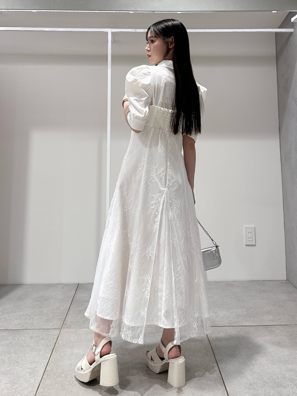 ホワイト系のワンピース、シルバー系のボディバッグ/ウエストポーチ、ホワイト系のサンダルを着用したレディースの夏コーディネートの3枚目の写真