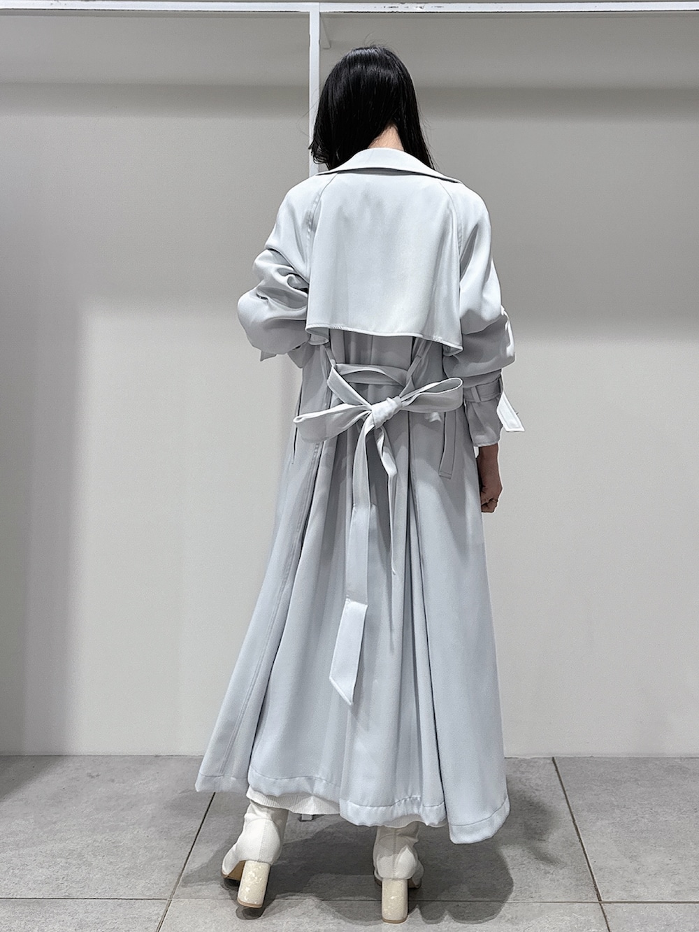 ブルー系のトレンチコート、ホワイト系のブーツ、ホワイト系のワンピースを着用したレディースの冬コーディネートの3枚目の写真