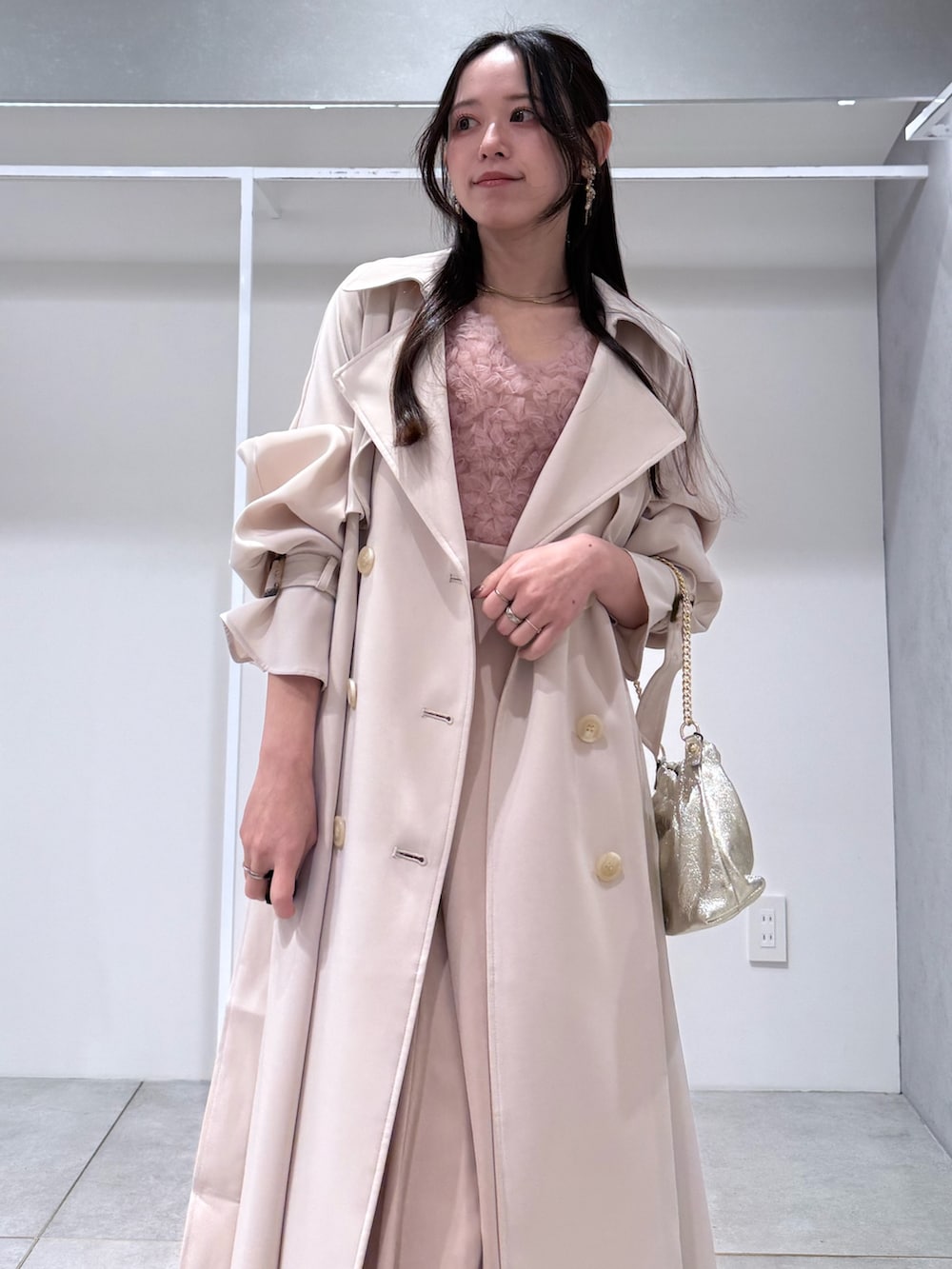 ホワイト系のトレンチコート、ピンク系のドレス、ゴールド系のショルダーバッグを着用したレディースの冬コーディネートの4枚目の写真
