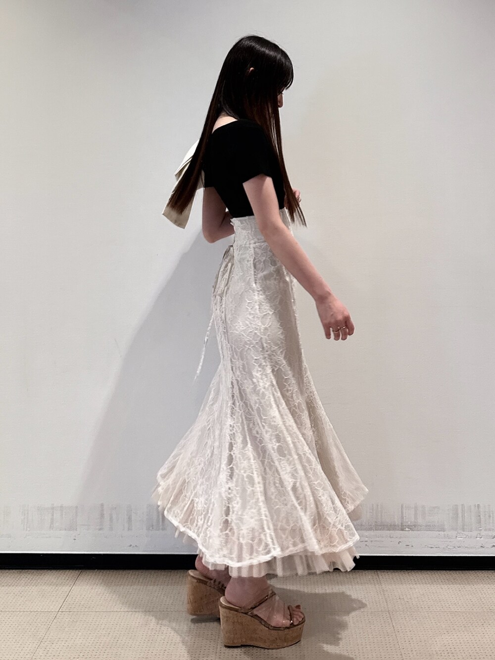 ブラック系のニット/セーター、ホワイト系のスカート、ブラウン系のサンダルを着用したレディースの夏コーディネートの6枚目の写真