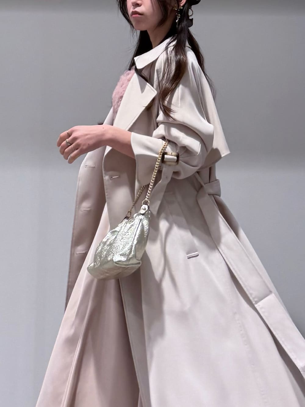 ホワイト系のトレンチコート、ピンク系のドレス、ゴールド系のショルダーバッグを着用したレディースの冬コーディネートの5枚目の写真