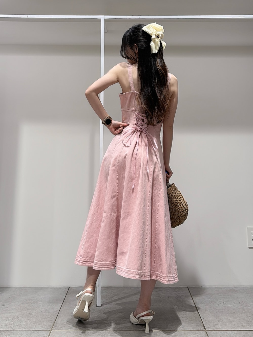 ピンク系のワンピース、ホワイト系のパンプス、ベージュ系のハンドバッグを着用したレディースの春コーディネートの3枚目の写真