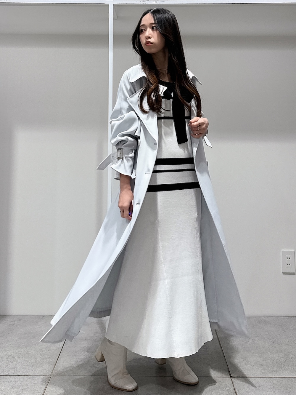 ブルー系のトレンチコート、ホワイト系のブーツ、ホワイト系のワンピースを着用したレディースの冬コーディネートの4枚目の写真