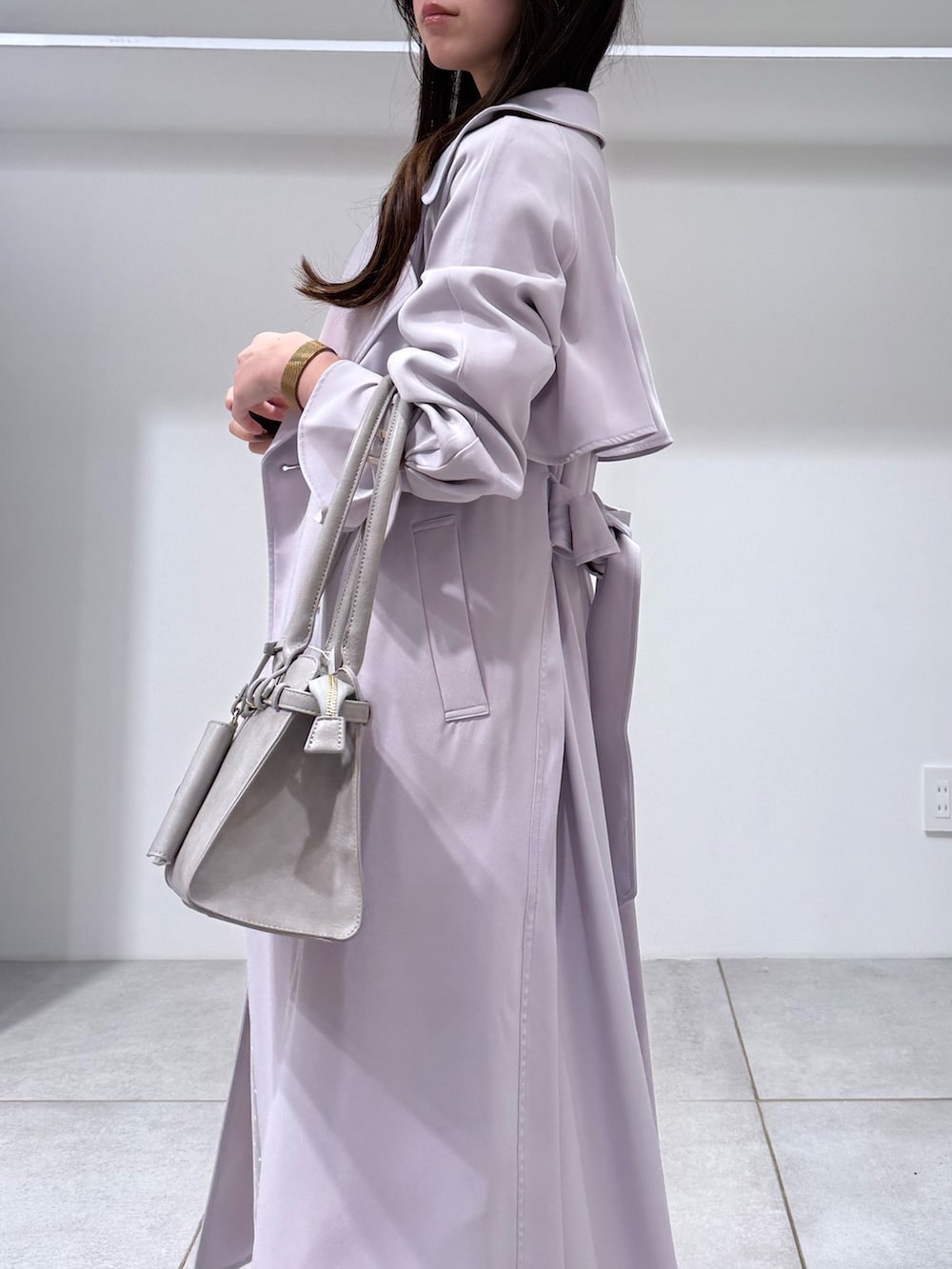 パープル系のトレンチコート、ホワイト系のワンピース、グレー系のハンドバッグを着用したレディースの冬コーディネートの7枚目の写真