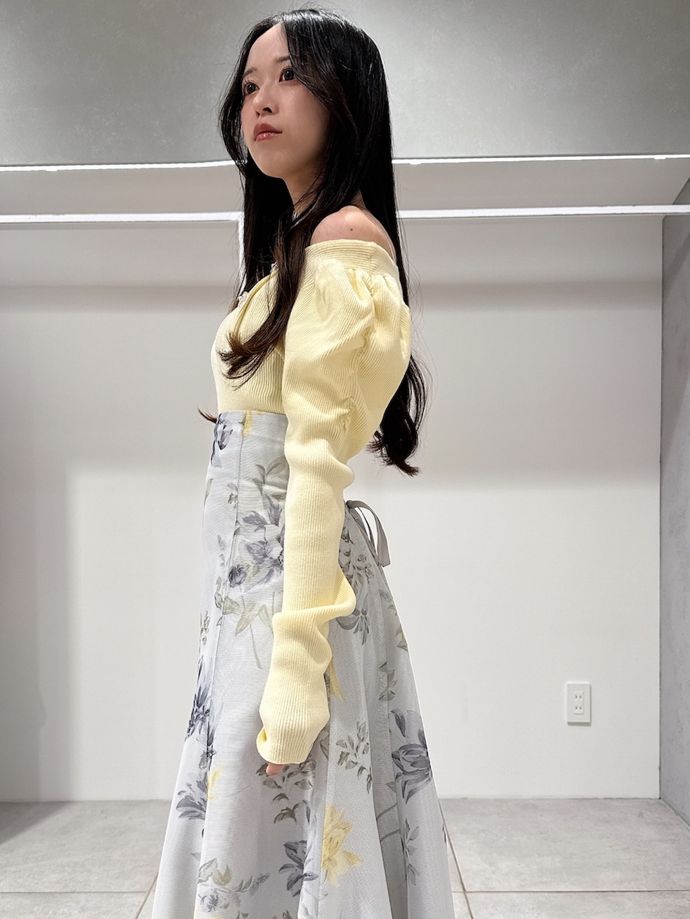 イエロー系のニット/セーター、グリーン系のスカート、ブラウン系のパンプスを着用したレディースの冬コーディネートの5枚目の写真