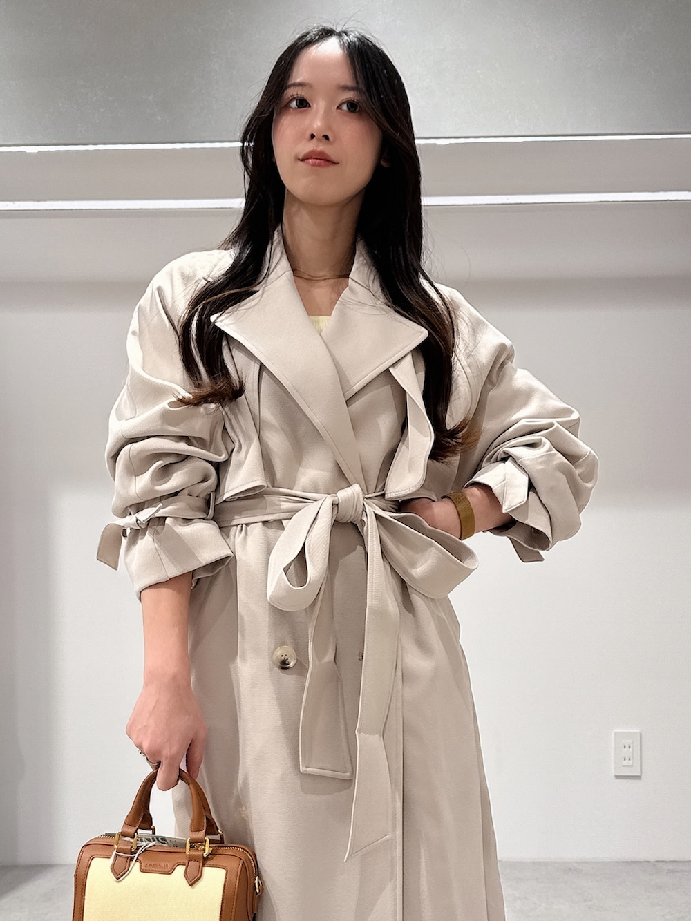 ベージュ系のトレンチコート、ブラウン系のハンドバッグ、ブラウン系のパンプスを着用したレディースの冬コーディネートの4枚目の写真