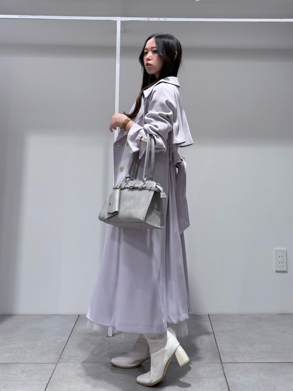 パープル系のトレンチコート、ホワイト系のワンピース、グレー系のハンドバッグを着用したレディースの冬コーディネートの2枚目の写真