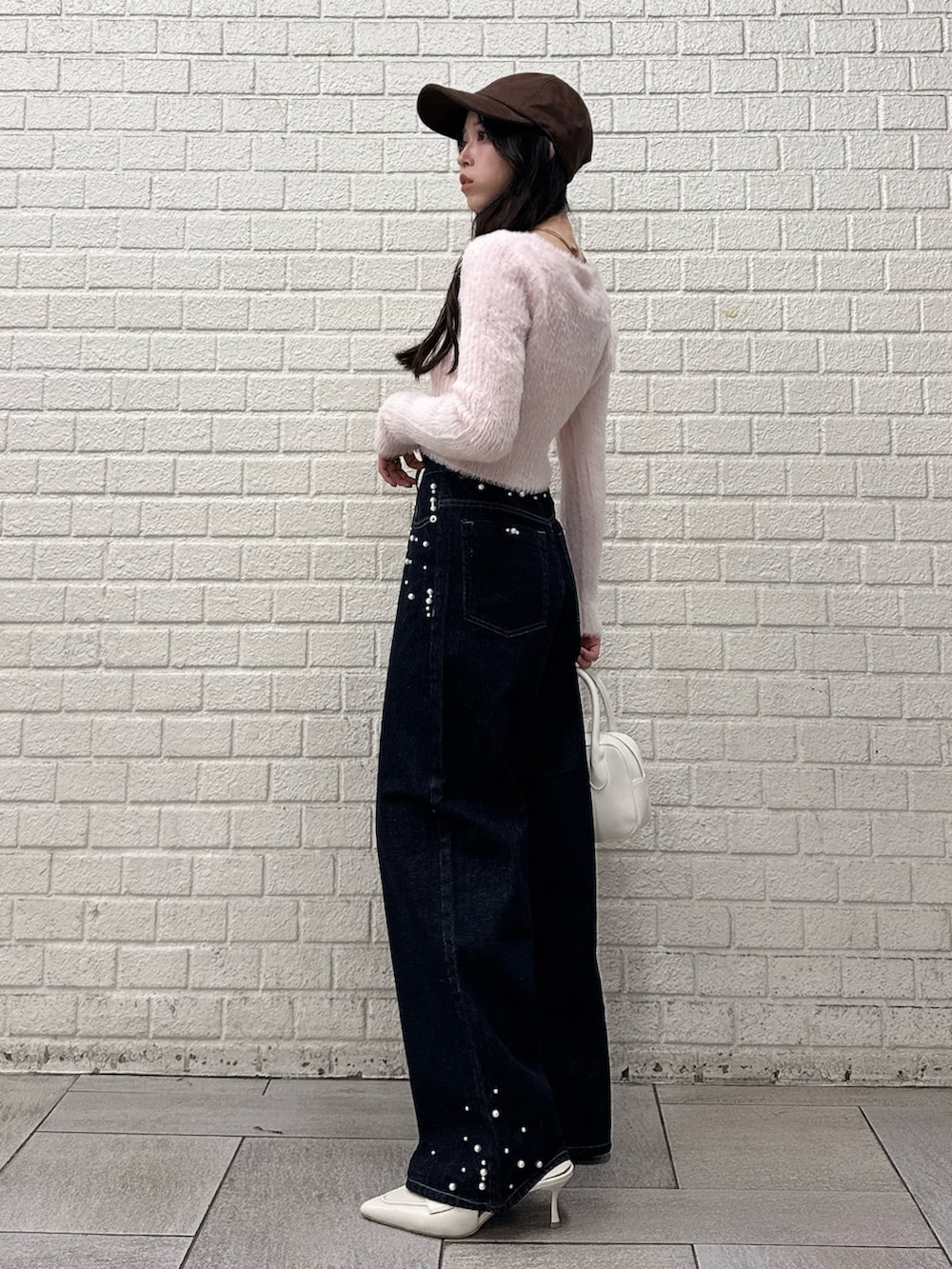 ピンク系のニット/セーター、ブルー系のデニムパンツ、ホワイト系のパンプスを着用したレディースの秋コーディネートの2枚目の写真