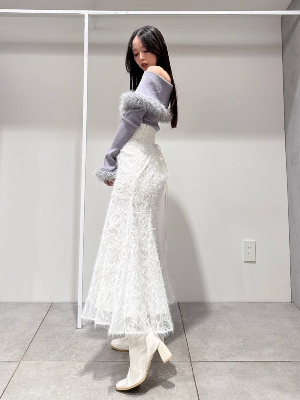 ホワイト系のスカート、ホワイト系のブーツ、グレー系のニット/セーターを着用したレディースの冬コーディネートの2枚目の写真