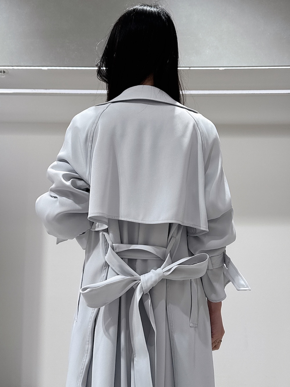 ブルー系のトレンチコート、ホワイト系のブーツ、ホワイト系のワンピースを着用したレディースの冬コーディネートの7枚目の写真