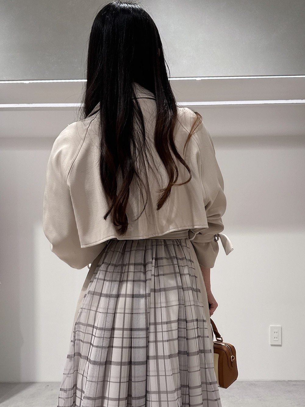 ベージュ系のトレンチコート、ブラウン系のハンドバッグ、ブラウン系のパンプスを着用したレディースの冬コーディネートの6枚目の写真