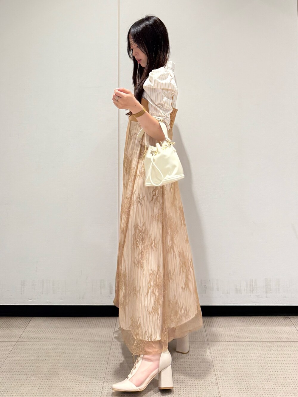 ベージュ系のワンピース、ホワイト系のハンドバッグ、ホワイト系のブーツを着用したレディースの夏コーディネートの2枚目の写真