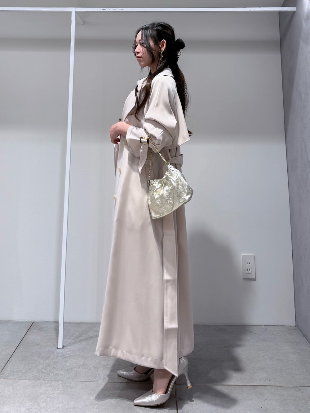 ホワイト系のトレンチコート、ピンク系のドレス、ゴールド系のショルダーバッグを着用したレディースの冬コーディネートの2枚目の写真