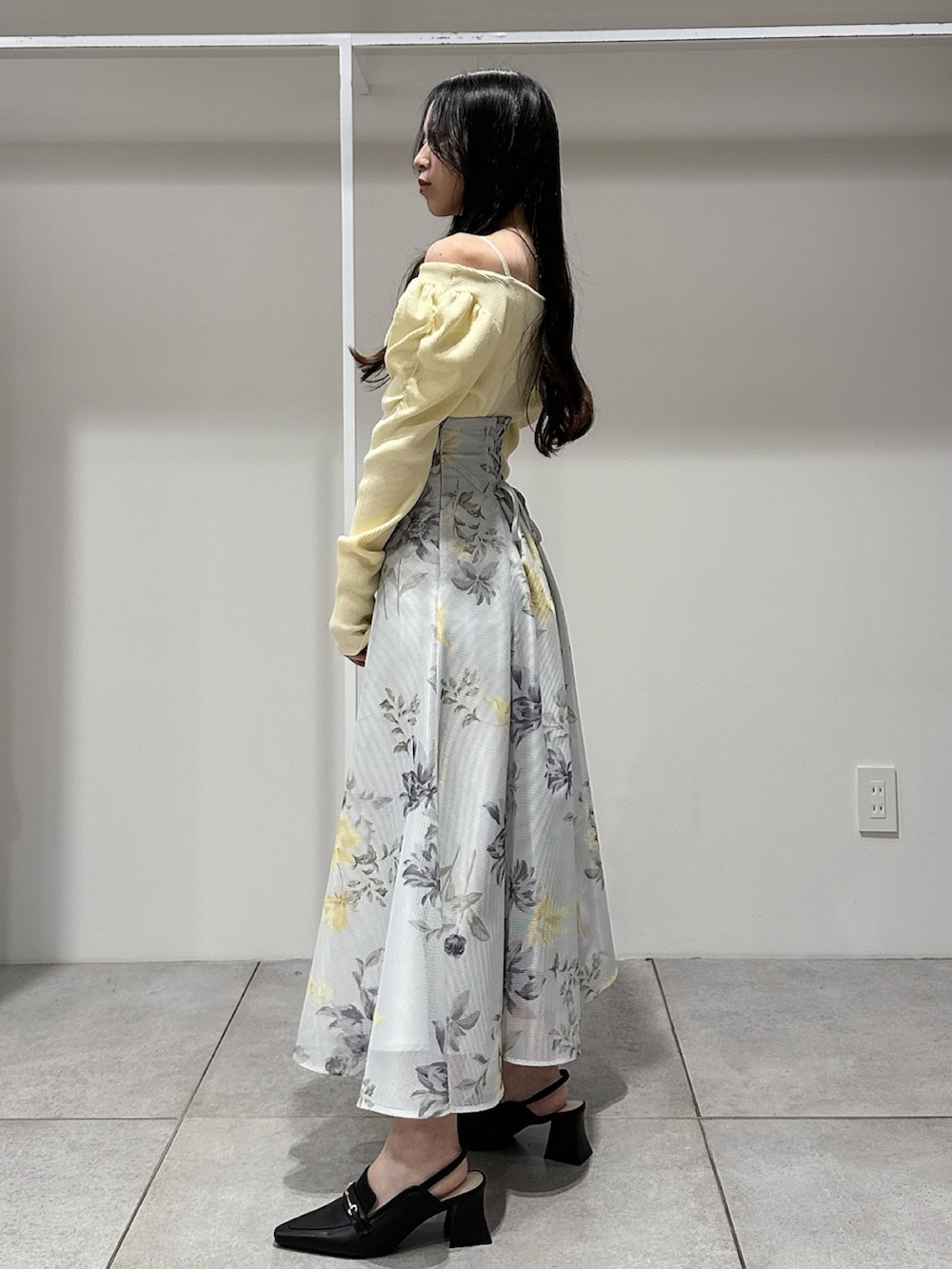 イエロー系のニット/セーター、グリーン系のスカート、ブラウン系のパンプスを着用したレディースの冬コーディネートの2枚目の写真