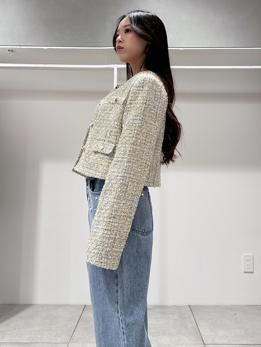 グリーン系のテーラードジャケット、ホワイト系のニット/セーター、ブルー系のデニムパンツを着用したレディースの春コーディネートの5枚目の写真