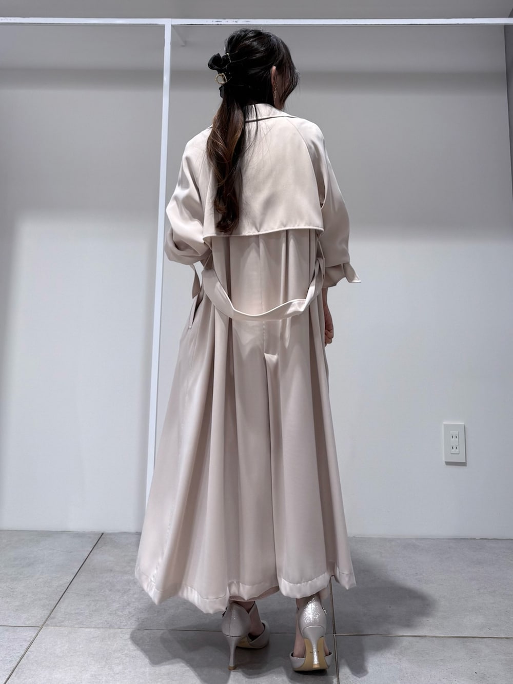 ホワイト系のトレンチコート、ピンク系のドレス、ゴールド系のショルダーバッグを着用したレディースの冬コーディネートの3枚目の写真