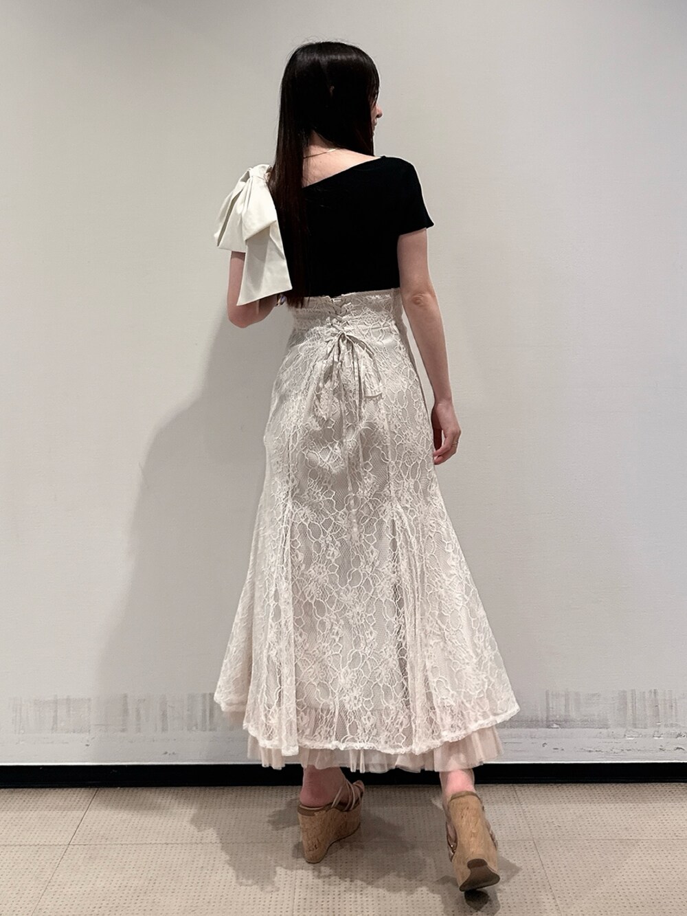 ブラック系のニット/セーター、ホワイト系のスカート、ブラウン系のサンダルを着用したレディースの夏コーディネートの4枚目の写真