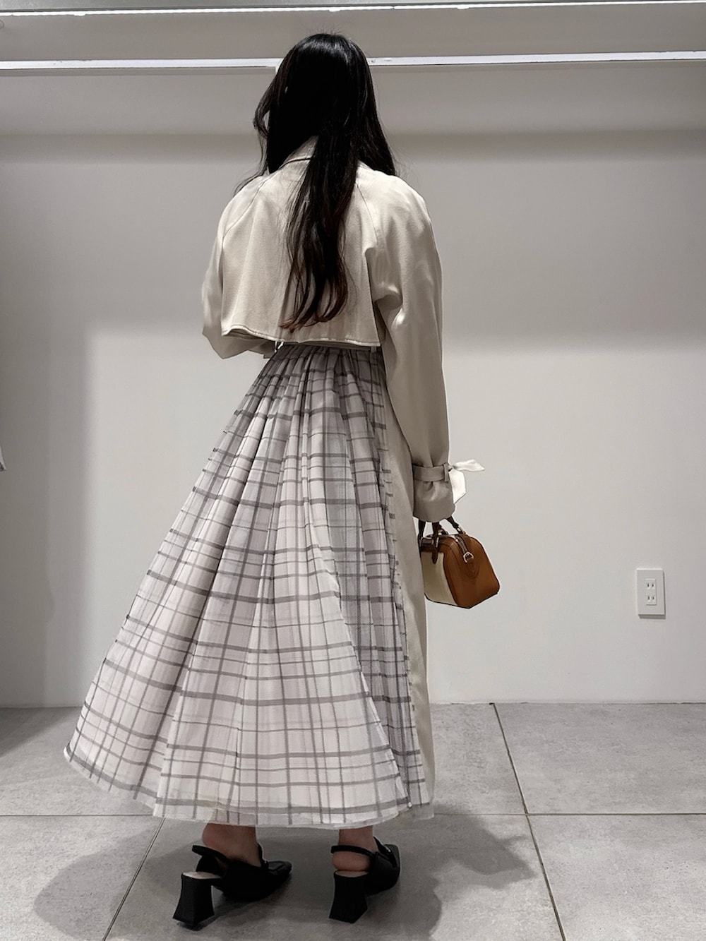 ベージュ系のトレンチコート、ブラウン系のハンドバッグ、ブラウン系のパンプスを着用したレディースの冬コーディネートの3枚目の写真