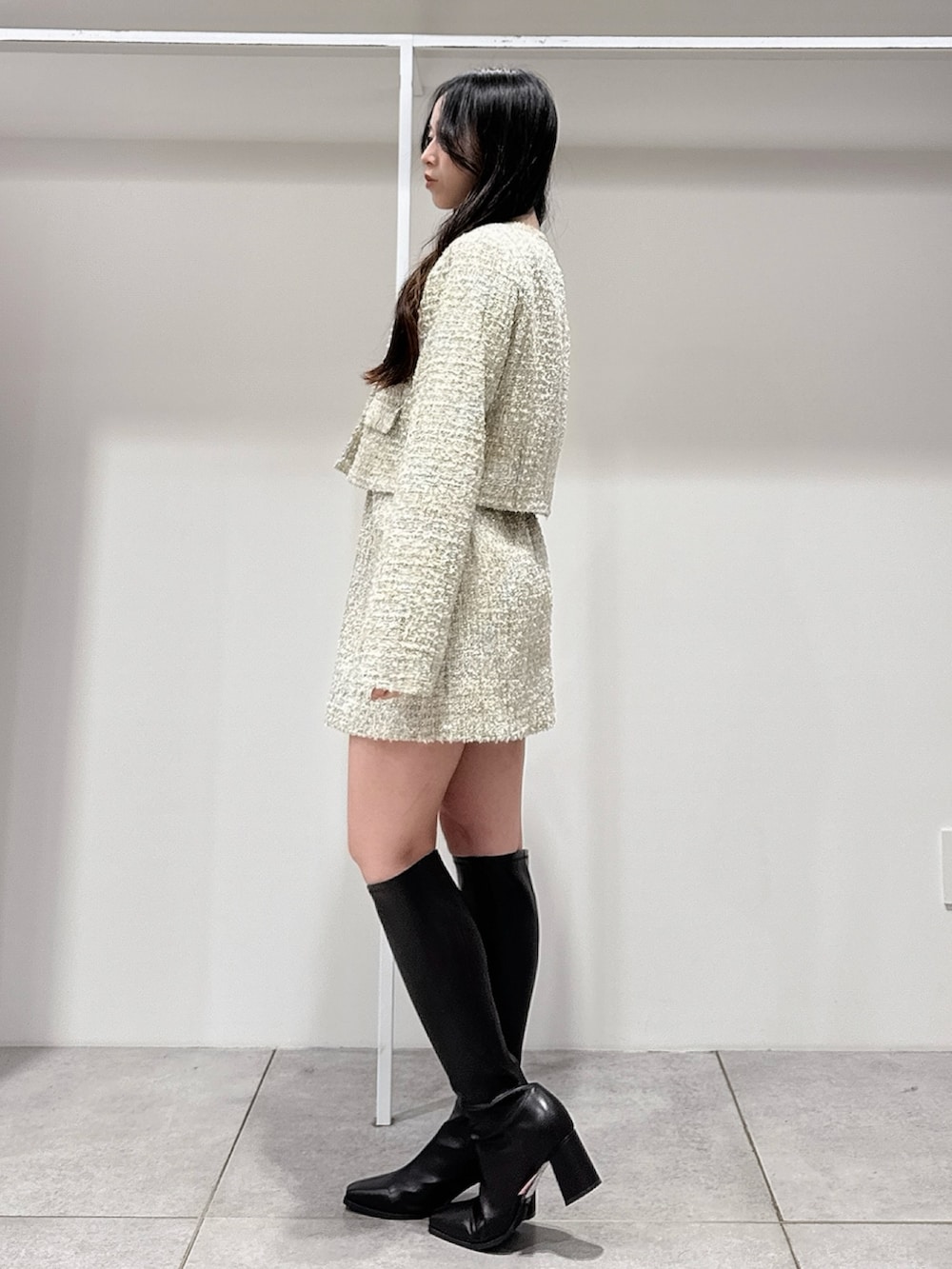 グリーン系のテーラードジャケット、グリーン系のスカート、ブラウン系のブーツを着用したレディースの春コーディネートの2枚目の写真