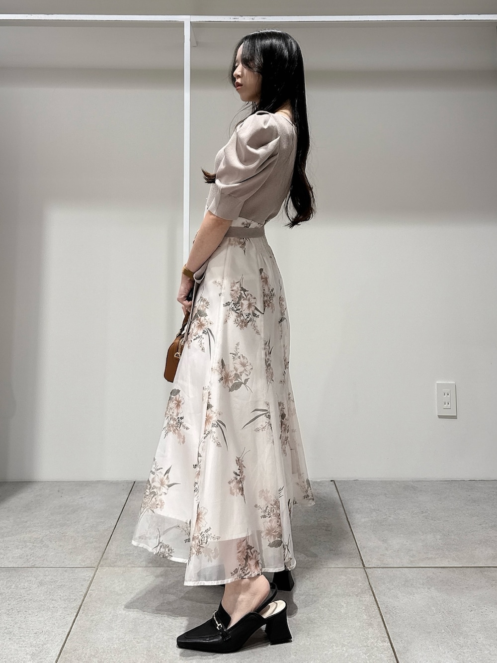 ベージュ系のワンピース、ブラウン系のハンドバッグ、ブラウン系のパンプスを着用したレディースの冬コーディネートの2枚目の写真