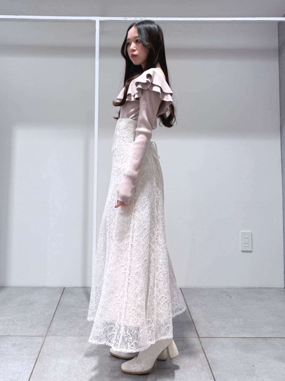 ホワイト系のハンドバッグ、ホワイト系のブーツ、ベージュ系のニット/セーターを着用したレディースの冬コーディネートの2枚目の写真