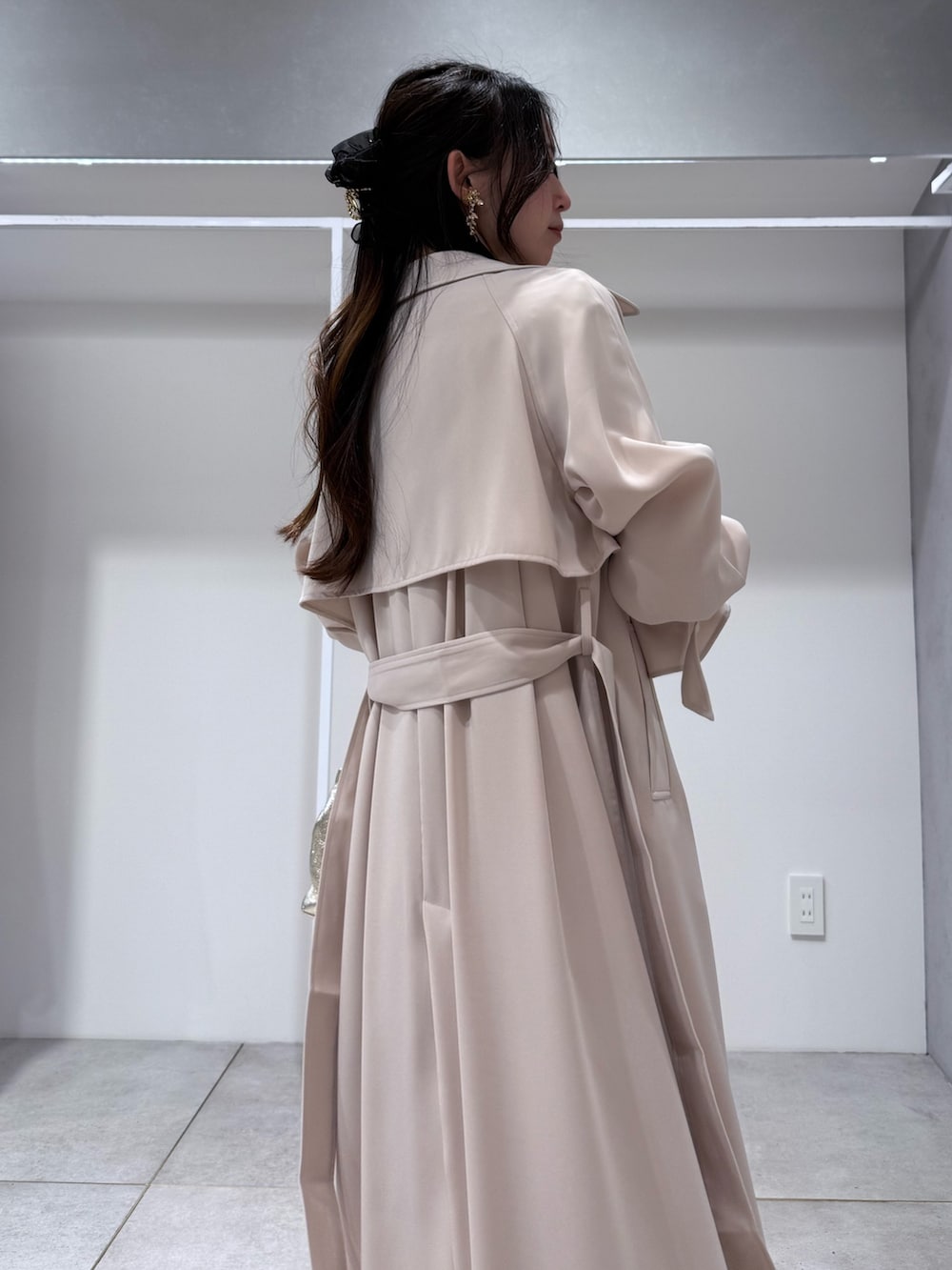 ホワイト系のトレンチコート、ピンク系のドレス、ゴールド系のショルダーバッグを着用したレディースの冬コーディネートの6枚目の写真